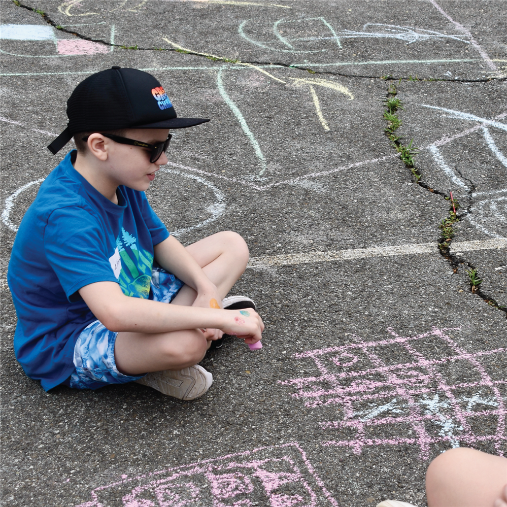  Student using chalk to draw on blacktop during field day.